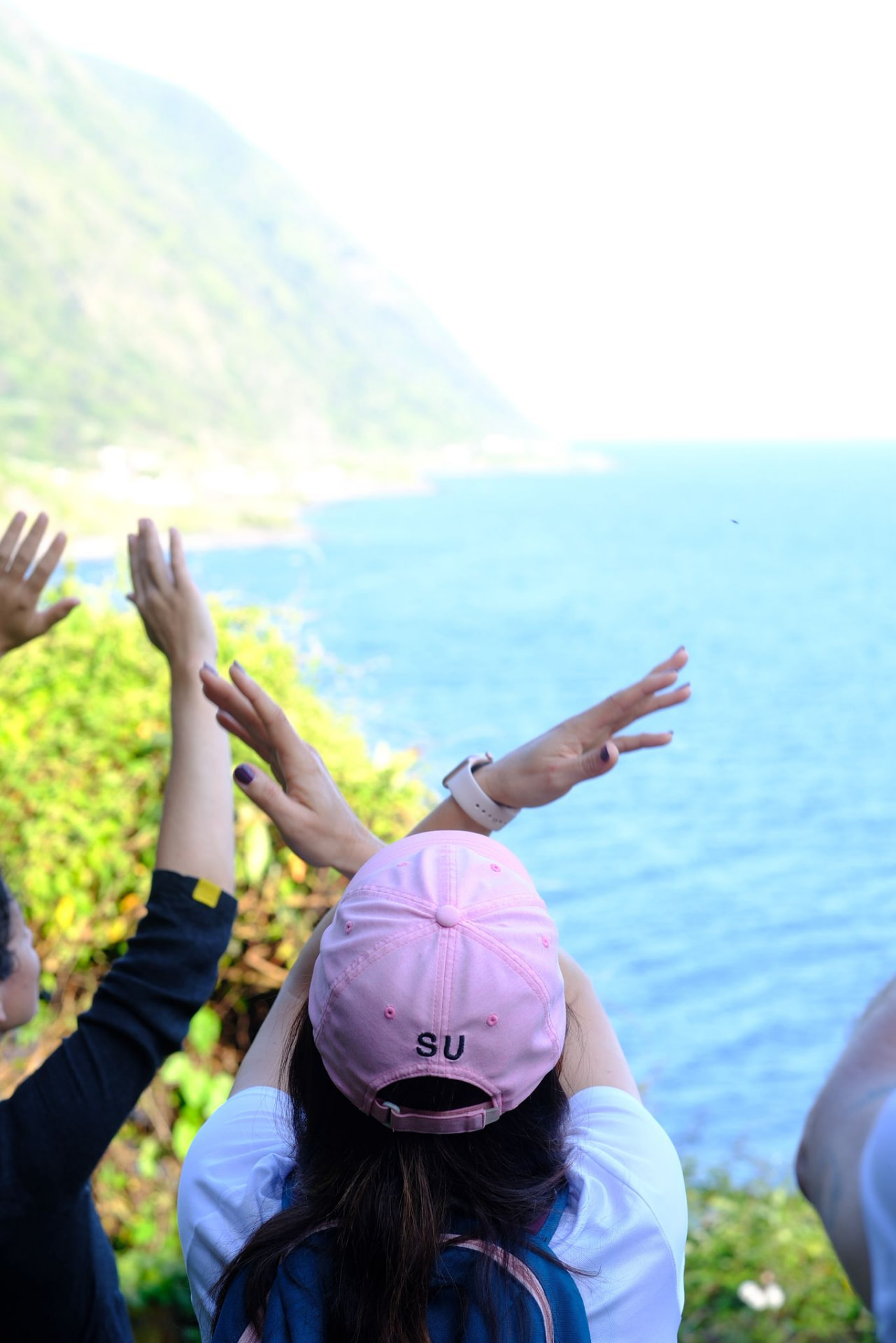 Participantes de braços erguidos frente à fajã e ao mar